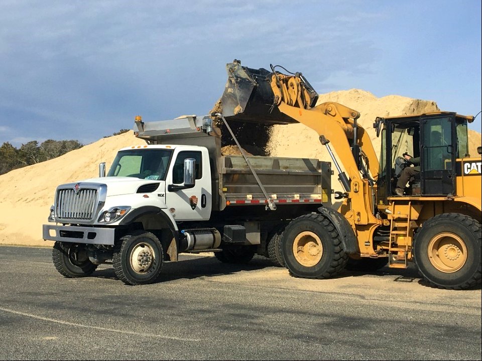 Maintenance crew working filling dump truck with sand for Inside Road repairs