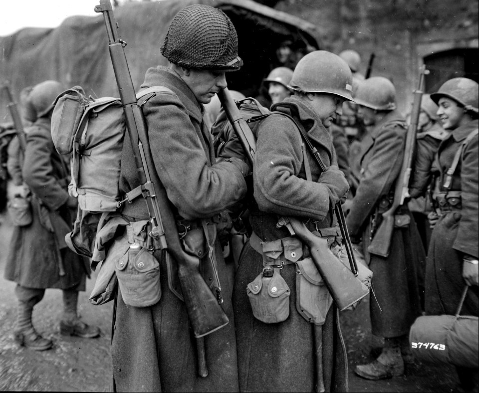 SC 374763 - Pvt. Zeb Turner, Bridgeport, Conn., adjusting the pack of Pvt. Robert [illegible]. Dunlap, Iowa, as infantrymen replacements prepare to leave for the front. Nancy, France, 15 November, 1944.