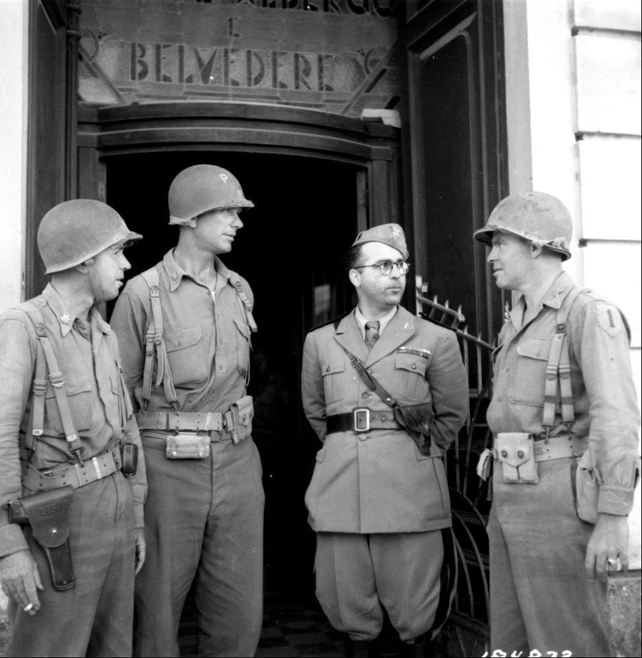 SC 184872 - L-R: Colonel R. Kilroe, N.Y.; Major Thomas Lancer, N.Y.; Saltala Macchia Guiseppe, Political Security Officer, Fascist Party, and Capt. Ray Regan, have a discussion after American entry to establish U.S. Military control of the city.