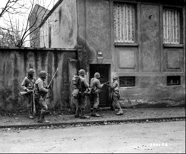 SC 270672 - Men of the U.S. 5th Inf. Div. attempt to break open the door of a house in Metz, France, so that they and their waiting comrades may clear the place of any enemy stragglers who may be in hiding. 19 November, 1944.