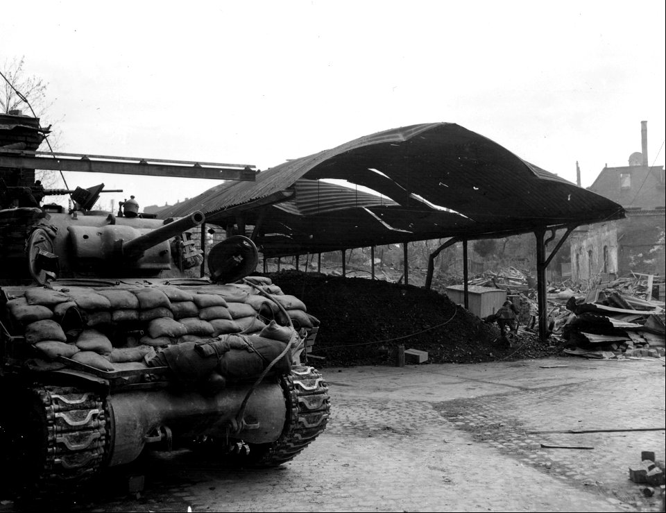 SC 337280 - Infantrymen cautiously advances past a tank of 781st Tank Bn., in factory section of Heilbronn.