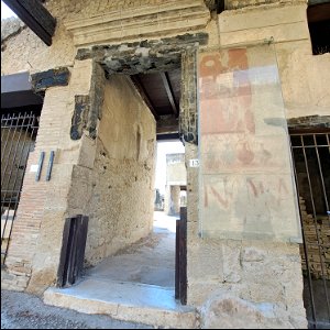 Original Wood of House of the Black Room and a sign which has an ode to a god the type and price of wine for sale and a theater advert  Herculaneum Italy