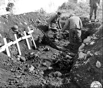 SC 195727 - German prisoners throwing dirt on Nazis interred in common grave. 28 September, 1944. photo