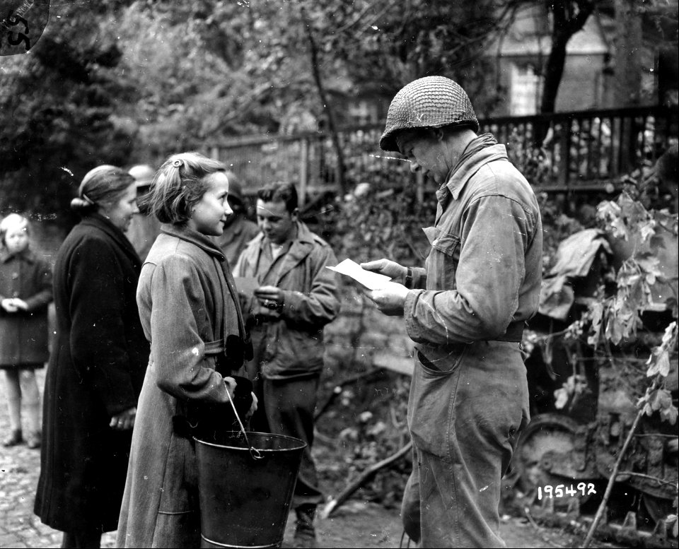 SC 195492 - T/5 Ray Tintera, Tampa, Fla., and Sgt. Elwood Johnson, Ogema, Wisc., check civilians at an outpost in Monschau, Germany. 16 October, 1944. photo