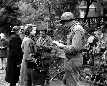 SC 195492 - T/5 Ray Tintera, Tampa, Fla., and Sgt. Elwood Johnson, Ogema, Wisc., check civilians at an outpost in Monschau, Germany. 16 October, 1944.