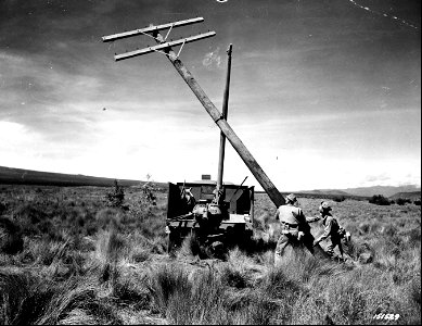 SC 151529 - The earth borer, used for digging post holes, is also used for lifting posts into place. Cpl. John Urban and Pvt. Rex Robinson guide the pole into place. Hawaii. photo