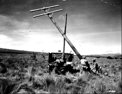 SC 151529 - The earth borer, used for digging post holes, is also used for lifting posts into place. Cpl. John Urban and Pvt. Rex Robinson guide the pole into place. Hawaii.