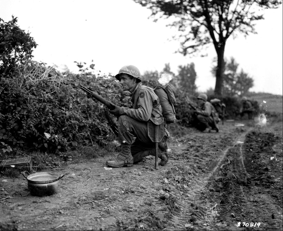 SC 270819 - Pvt. Nicholas Pappas of Canton, Ohio, peers through a hedge as his company advances towards a pillbox along the Siegfried Line.