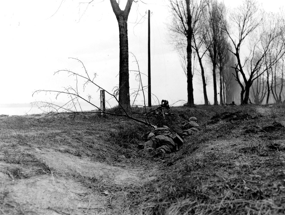 SC 270637 - Rhine Crossing: Two Yank machine gunners hit a ditch on East Bank of Rhine as enemy artillery shell comes in.