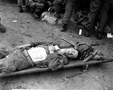 SC 348678 - Pfc. Thomas Conlon, Closter, N.J., 21st Inf. Regt., 24th Inf. Div., lies on a stretcher at a medical aid station, after being wounded while crossing the Naktong River in Korea. photo