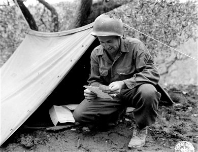 SC 396909 - S/Sgt. Claude W. Small, of Summit Street, Boothwyn, Pennsylvania, who is serving with the 349th Infantry Regiment of the 88th Division, forgets his drab surroundings as he reads a letter from home. photo