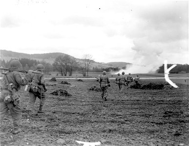 SC 270885 - Infantrymen of 11th Armored Division, 3rd U.S. Army, advance toward Austrian border near Kepple, Austria, shortly before the end of war in Europe. Smoke is from mortar blast. photo