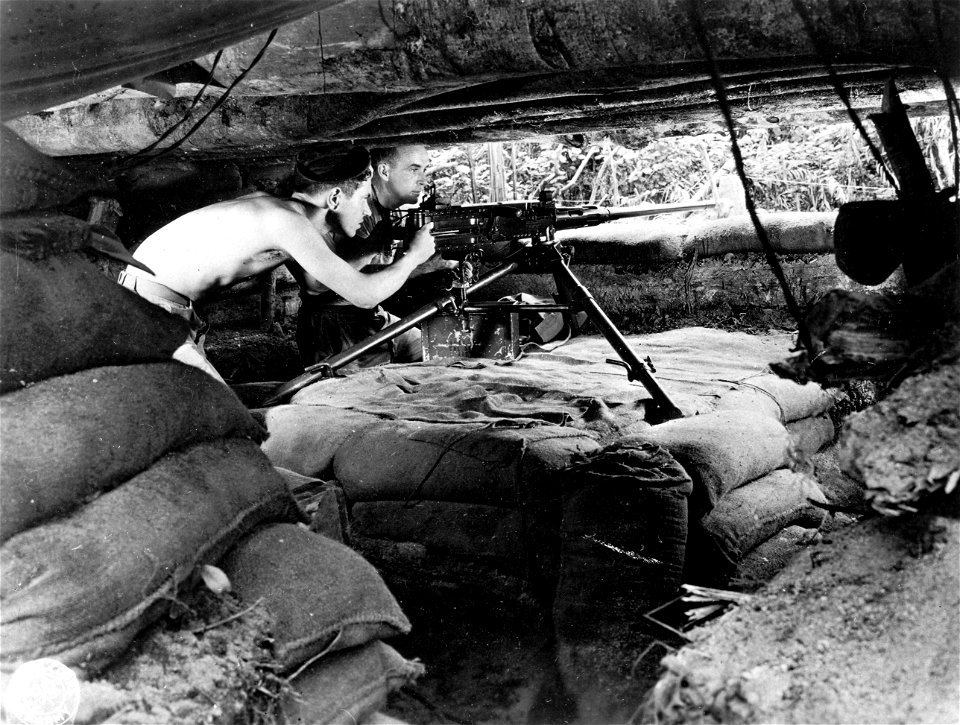SC 334755 - Pvt. William J. Burick of New York City, N.Y., gunner, and Pfc. Lawrence E. Bratton of Swanton, Ohio, ammunition fetcher, man a .50 caliber machine gun in a dugout on the 37th Division Command Post's defense line.