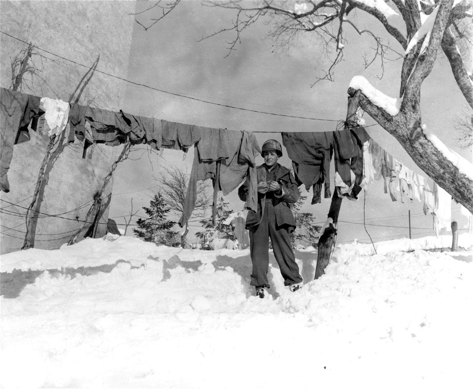 SC 329877 - Pfc. Merlyn R. Lehman, Orangeville, Ill., 34th Recon., 34th Div., checks his laundry in deep snow. 9 January, 1945.