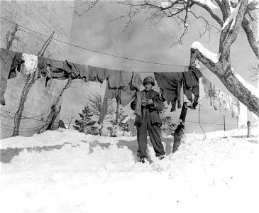SC 329877 - Pfc. Merlyn R. Lehman, Orangeville, Ill., 34th Recon., 34th Div., checks his laundry in deep snow. 9 January, 1945. photo