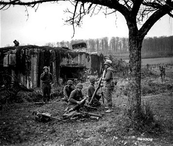 SC 364305 - 45th Division mortar crew, which is sheltered behind the Maginot Line pill-box near Lembach, prepares to fire 81mm shells at enemy. photo