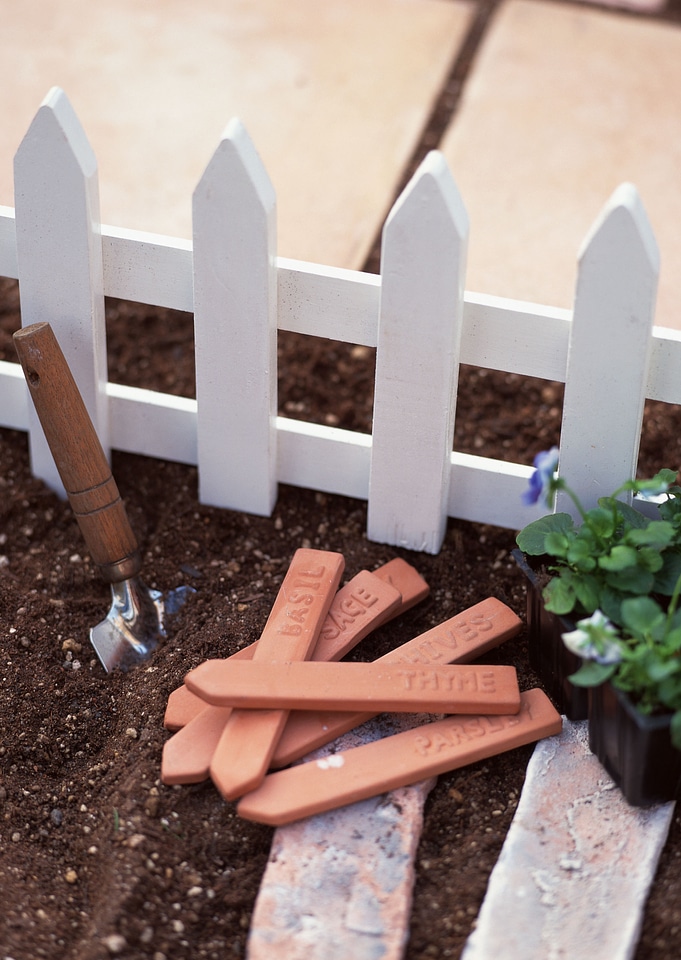 open compost bin with garden tools and herb name tag