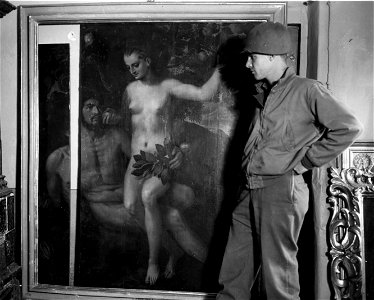 SC 374650 - Lt. William S. Leinberger, southern Cal., "C" Battery, 337th F.A. Bn., 88th Div., inspects the Adam and Eve painting by Frans Floris I, which was bruised and torn in transit.