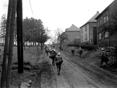 SC 335268 - 94th Division infantrymen, supporting 10th Armored Division of 3rd U.S. Army, move out of Hermeskeil, Germany. 18 March, 1945.
