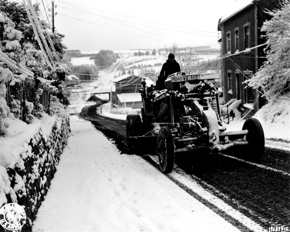 SC 196219-S - A member of an Engineer unit uses a grader to clear the first snowfall off a road near Butgenbach, Belgium. 1st Army area, 9 November, 1944. photo