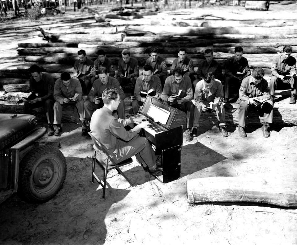 SC 184755 - Organist, T/5 Cleo Huizengen of Zealand, Mich., 32nd Div., at organ, with congregation in background. photo