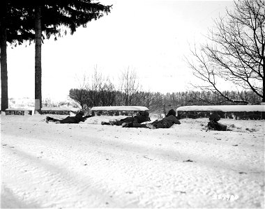 SC 329980 - Men of the 202nd Combat Engineers, 8th Corps, lie in shelter of a snow-covered wall as they fire at sniper on hill in Bois De Chabry, near Herbaimont, Belgium. 16 January, 1945. photo
