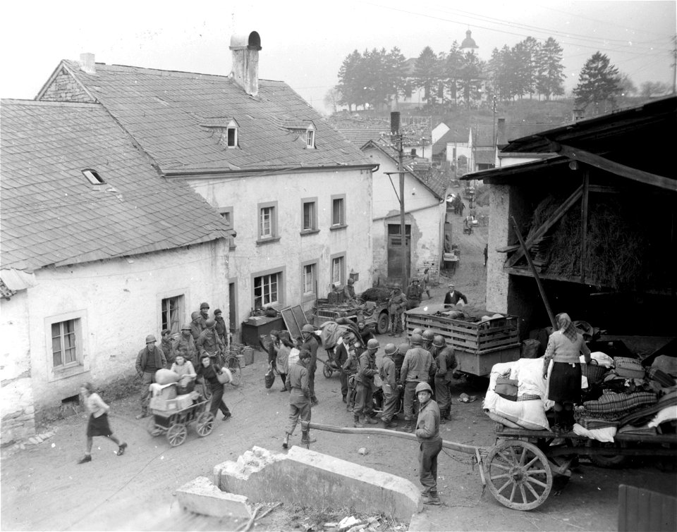 SC 336786 - American soldiers look on as German civilians move their belongings in the town of Sulm, Germany. 6 March, 1945.