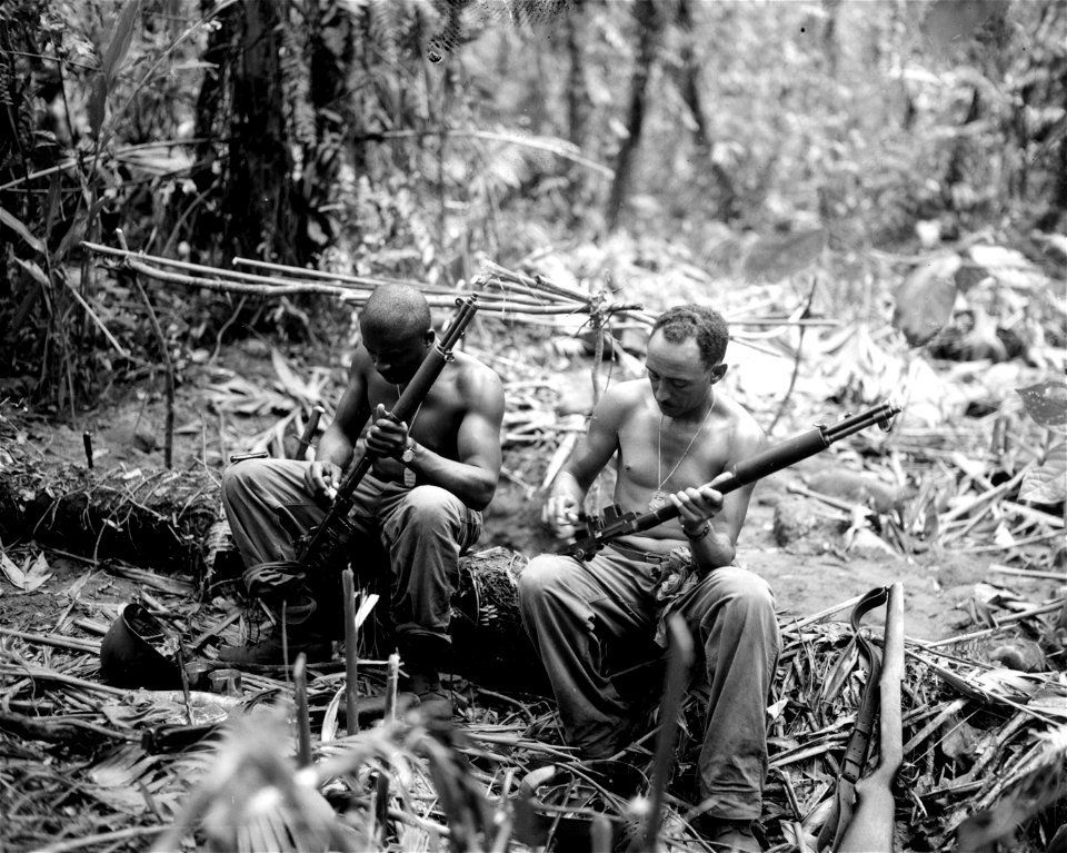 SC 364565 - Sgt. John C. Clark, Lorman, Miss., and S/Sgt. Ford M. Shaw, Tuscon, Arizo., (l-r) clean their rifles in bivouac area alongside the (illegible) Trail, Bogainville.