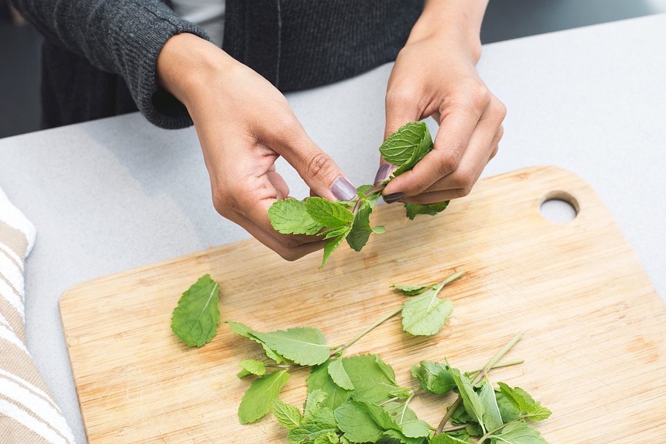 mint leaves being ripped on a cutting board