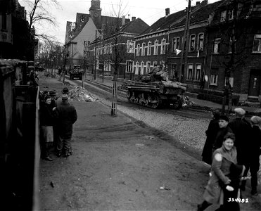 SC 334982 - German civilians stand on the street in Krefeld, Germany, and watch the 2nd Armored Division, 9th U.S. Army troops pass by. 3 March, 1945.