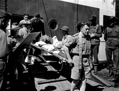 SC 170444 - A casualty from the Battle of Milne Bay is carried off an Australian Red Cross ship to an awaiting ambulance which will take him to a hospital, somewhere in Australia.