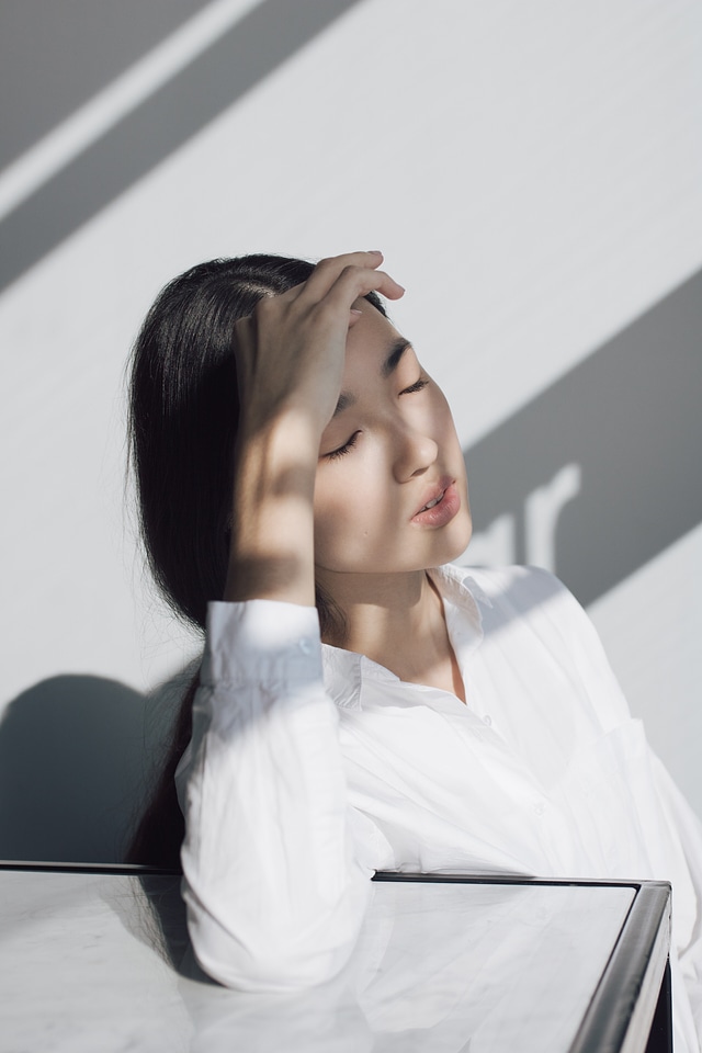 beautiful blond girl covering face by hand of bright sun light