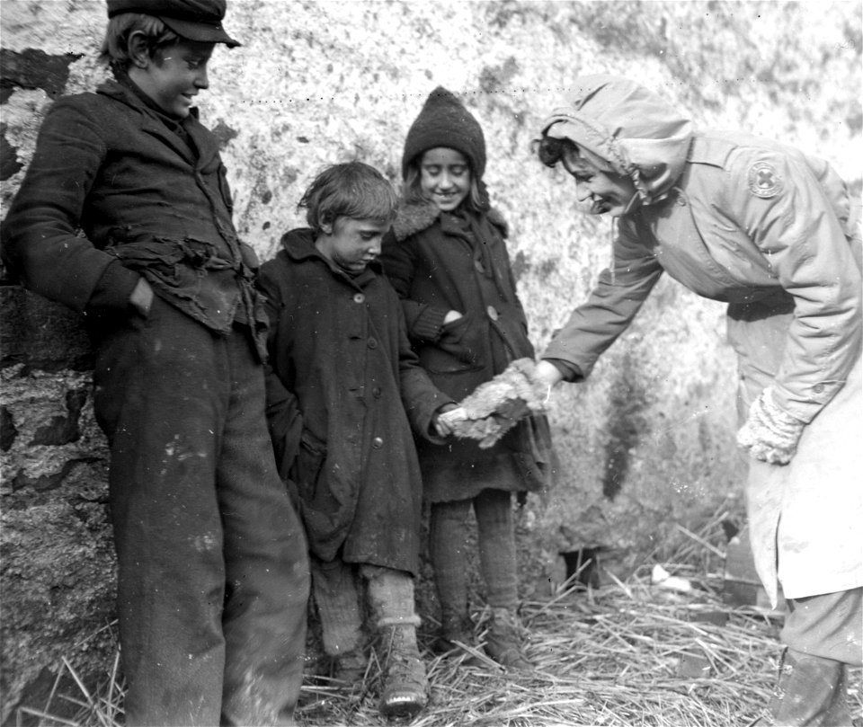 SC 329791 - Red Cross clubmobile worker Marjorie Wiegland, of Eagle River, Wisc., offers stick of gum to Belgian children near St. Vith. 10 February, 1945.