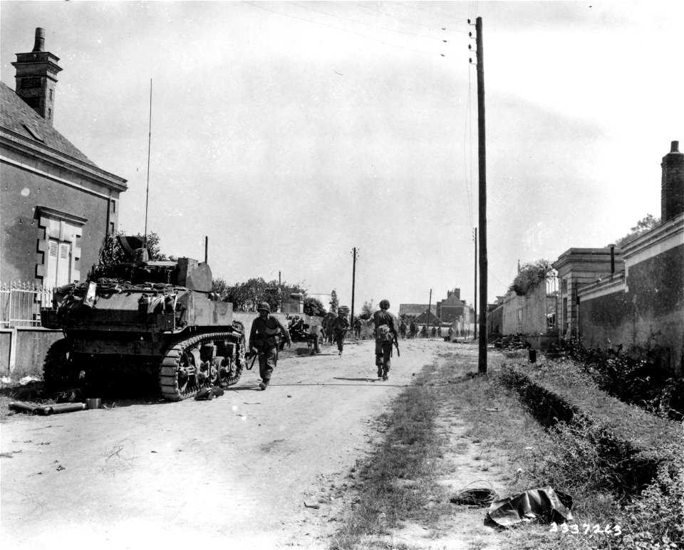 SC 337263 - American troops move into the village while it is under fire. The tank halts momentarily to secure additional ammunition. Angers, France. 10 August, 1944.