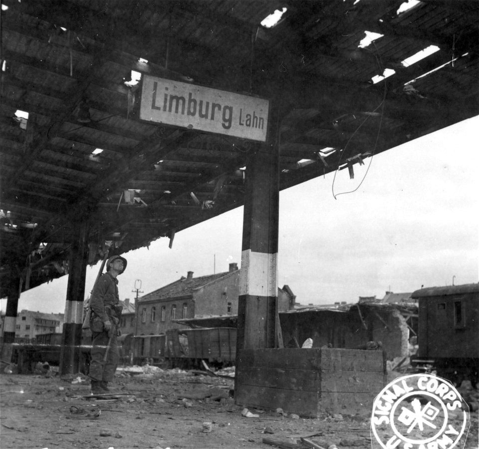 SC 335290 - Third U.S. Army soldier looks at sign in Limburg, Germany, marshalling yards, scene of Allied bombing raids. 1 April, 1945.