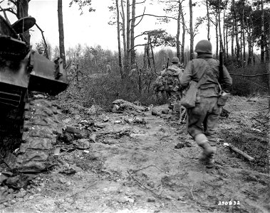 SC 270832 - Infantrymen of the 9th Division, U.S. First Arm, move past Sherman tank hit between Froitzheim and Thum, Germany. 1 March, 1945. photo