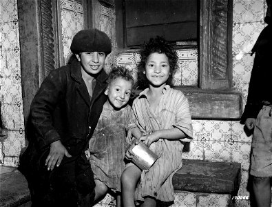 SC 170066 - Three Arabic children waiting to receive their daily ration of milk at a distribution point in North Africa. photo