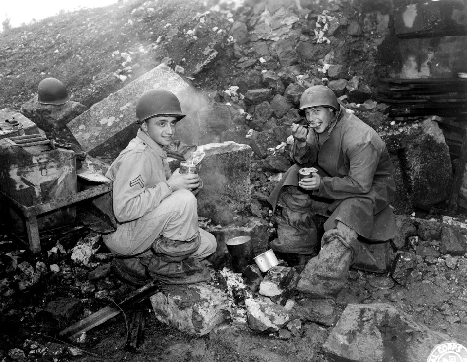 SC 396831 -  L-R: Cpl. John L. Hammer, New York City, Pfc. Raymond M. Jankowski, of Philadelphia, Penn., settles down to eat a can of hot "C" rations after a cold "wallow in the mud of sunny Italy".