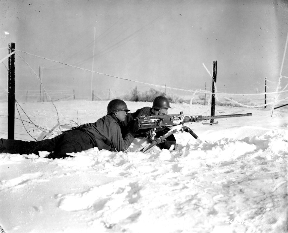 SC 364312 - Gunner Pvt. Nick Hotolsky, Russellton, Pa. and gunner Pfc. Roman Vinicki, South Bend, Ind., laying in the snow and guarding a road junction with their .50 caliber machine gun.