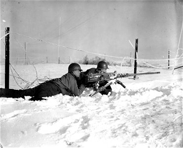 SC 364312 - Gunner Pvt. Nick Hotolsky, Russellton, Pa. and gunner Pfc. Roman Vinicki, South Bend, Ind., laying in the snow and guarding a road junction with their .50 caliber machine gun. photo