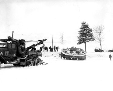 SC 199013 - American ordnance use a wrecker to right an overturned M-4 tank, which due to the heavy snow in Belgium, skidded off the roadway and down an embankment. 10 January, 1945. photo