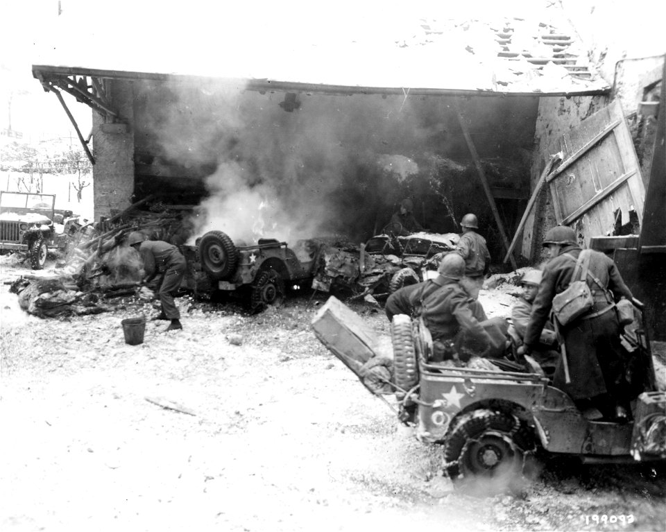 SC 199093 -  While enemy shells drop in the vicinity, American soldiers of the 26th Division unload supplies for 3rd Battalion outside a town in Luxembourg.