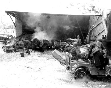 SC 199093 - While enemy shells drop in the vicinity, American soldiers of the 26th Division unload supplies for 3rd Battalion outside a town in Luxembourg. photo