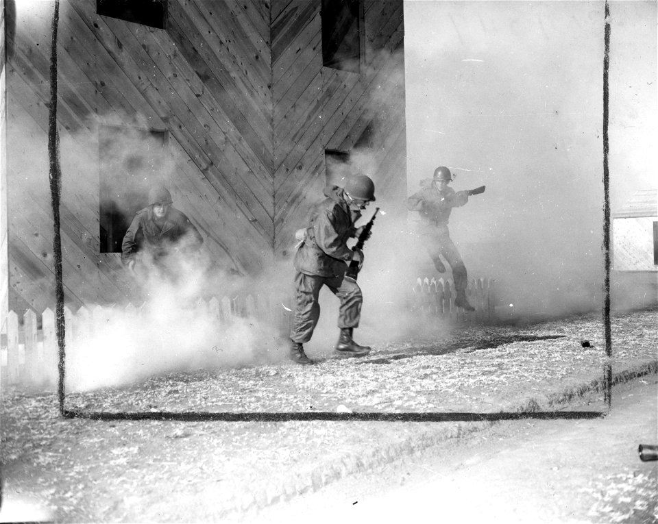 SC 364249 - Through billowing smoke, three men from Company B, 83rd Engr. Bn., Fort Sill, Okla., push on toward the next house in realistic training at Fort Sill's Combat Village. 17 January, 1951.