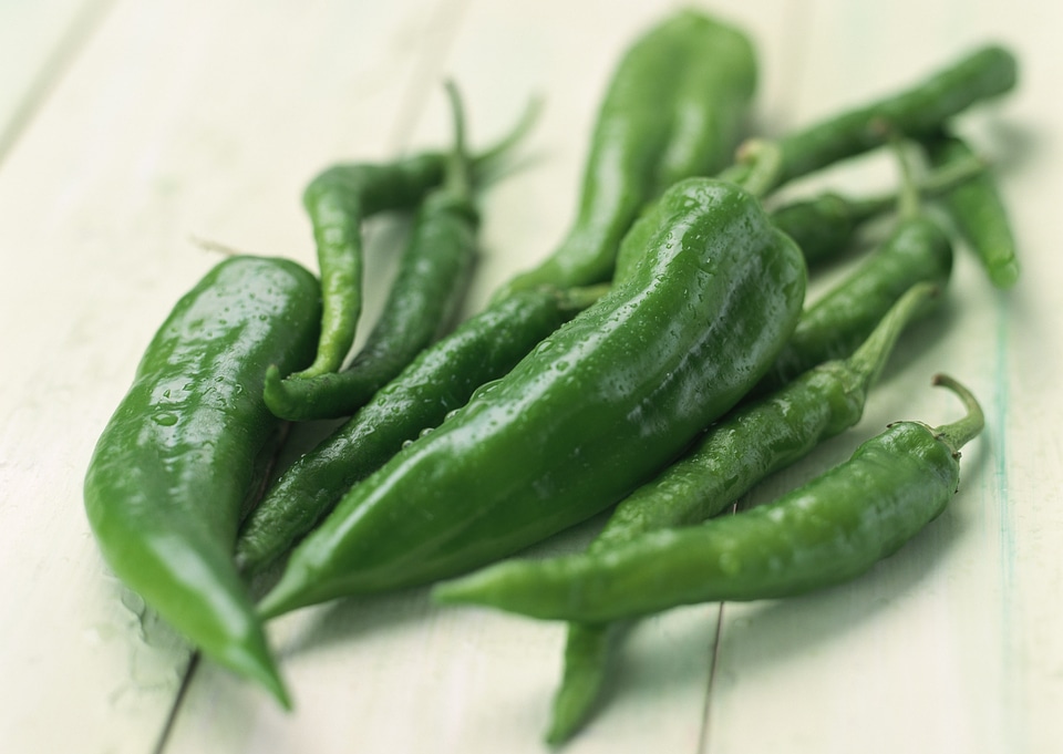 Long green chili peppers resting on wooden board surface photo