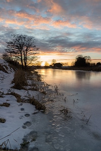 Winter forest on the river at sunset
