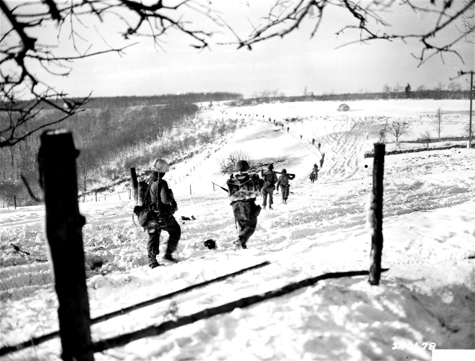 SC 270678 - Preceded by a tank for heavy support, men of the 1st Battalion, 10th Regiment, 5th Infantry Division, file out of Nachmanderscheid, Province of Luxembourg, carrying their munitions of war.
