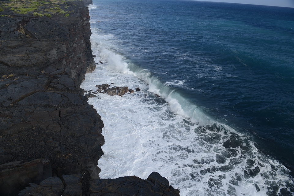 Waves crash along the black lava rock cliffs in the Hawaii