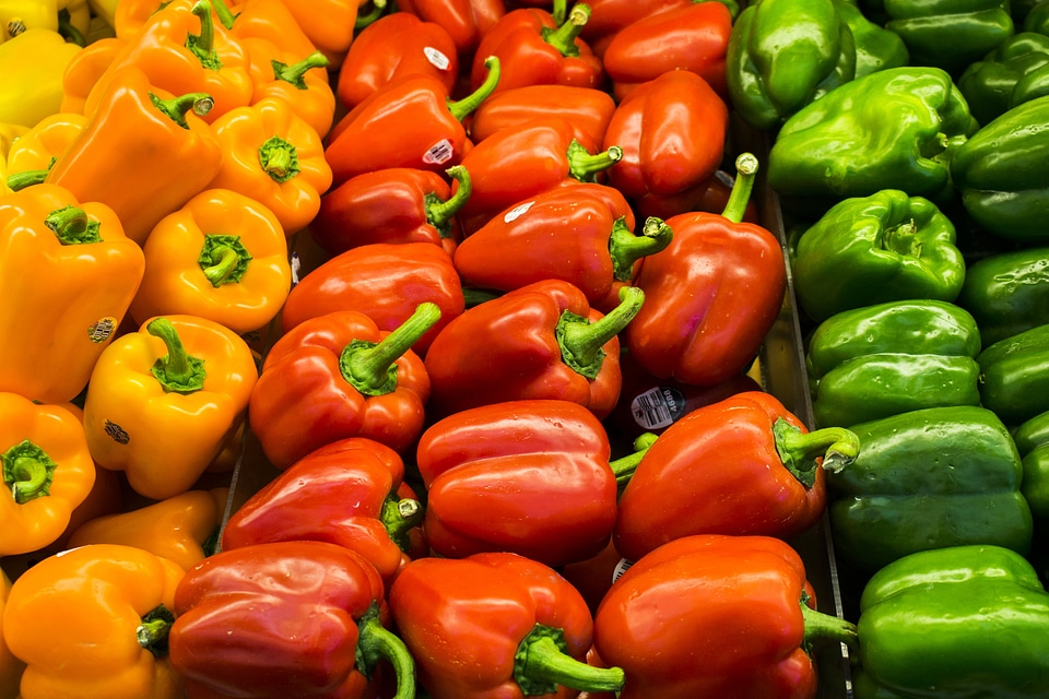 Red, orange and green peppers at a vegetable market all piled up photo