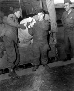 SC 405017 - T/Sgt. Ralph Hagmann, 5137 Warren Ave., Norwood, Ohio, with a quartermaster company, 66th Infantry Division, helps "Shorty", a Russian liberated from a German labor labor camp...